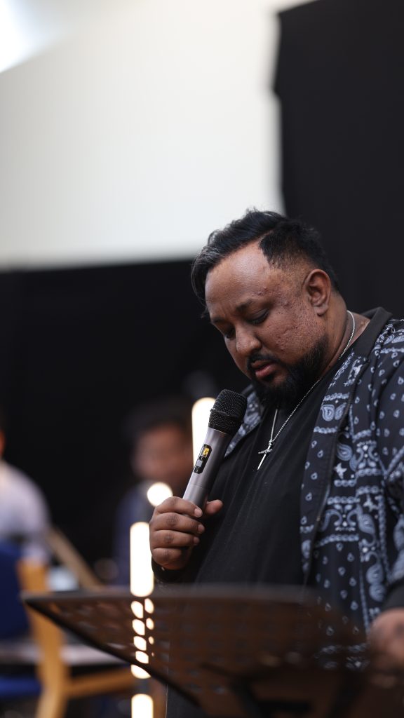Preacher holding a microphone and looking down at his notes