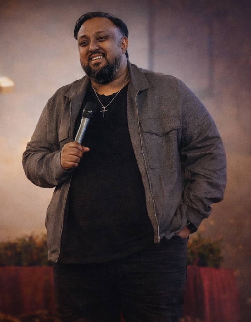 Pastor Andrew Navakumar smiling, holding a microphone